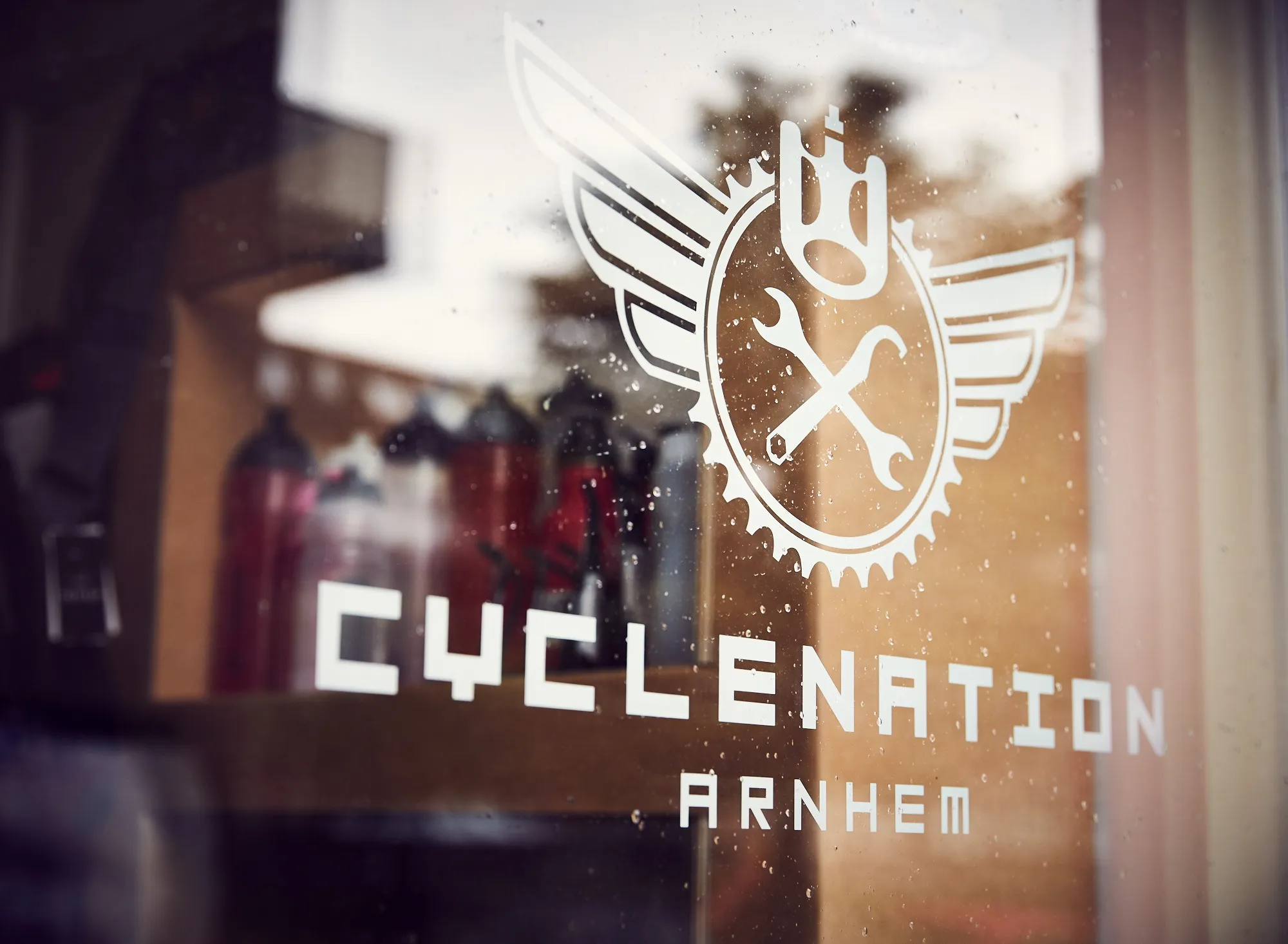 Het CycleNation-logo op de winkelruit, met regendruppels